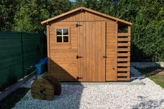 A wooden garden shed standing on a concrete foundation in a garden.